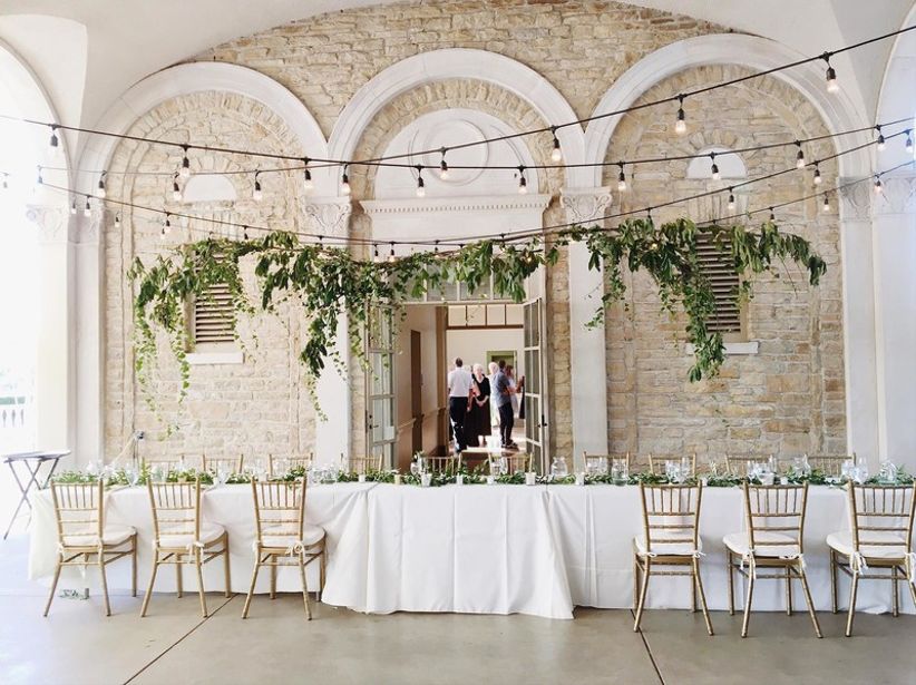 romantic woodland wedding idea — hanging greenery and string lights above main table